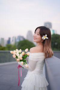 Portrait of young woman standing against sky