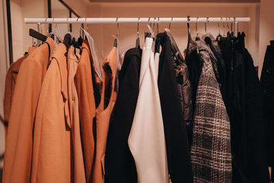 Designer fashion autumnal outfits hanging in a row at the backstage.