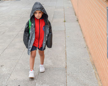 Portrait of boy walking on footpath