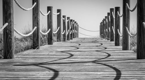 Surface level of wooden footbridge against clear sky