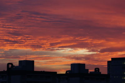 Silhouette cityscape against orange sky