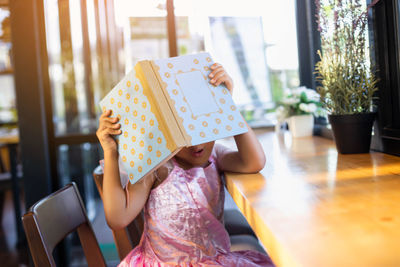 Full length of girl holding chair at home