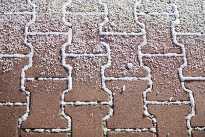 Partially snow-covered red cobblestone sidewalk. close-up view.