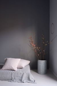 Vase by bed against gray wall at home