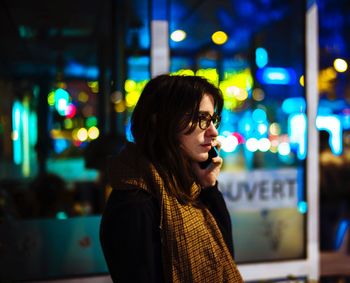 Portrait of woman looking at illuminated city at night