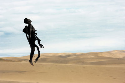 Teenage boy in costume on desert against sky