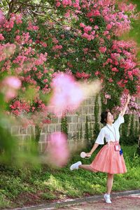 Woman standing against pink flowering plants