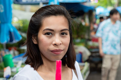 Close-up portrait of woman having pink popsicle outdoors