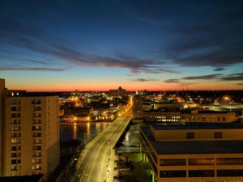 High angle view of illuminated city against sky at sunset