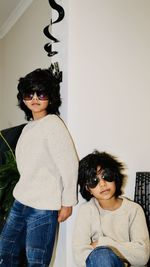 Portrait of young siblings wearing sunglasses while standing against white background