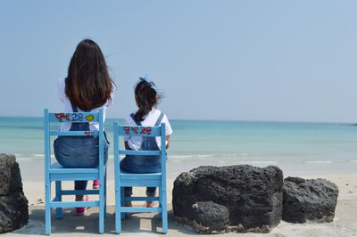 Rear view of women sitting on beach