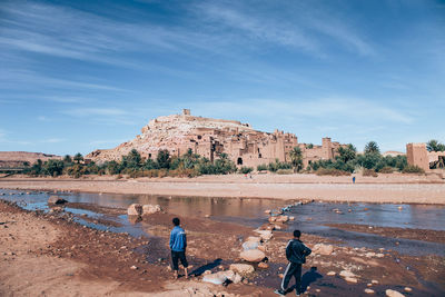 People working on shore against sky