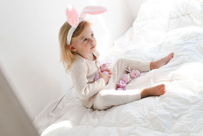 Kid, girl wearing bunny ears playing with colourful eggs on bed.concept of spring and easter holiday