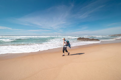 Rear view of woman walking at beach against sky