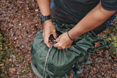 High angle view of man opening backpack on field