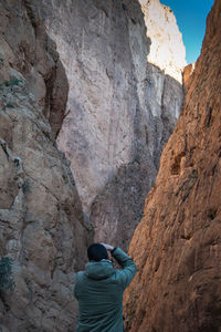 Rear view of man standing against rocky mountain