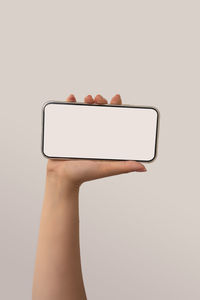 Close-up of woman holding smart phone against white background