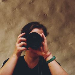 Close-up of woman photographing against wall