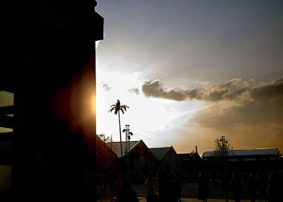 Silhouette people by building against sky during sunset