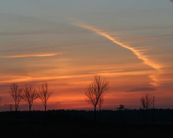 Silhouette bare trees on landscape against sky during sunset