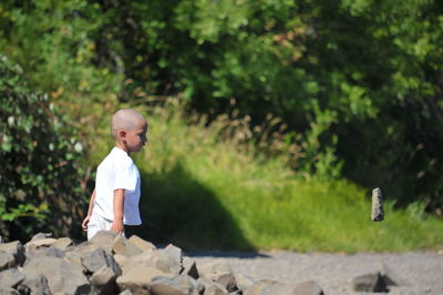 Side view of young boy throwing a stone