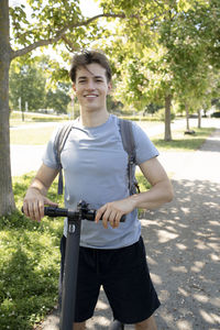 Portrait of young man standing against trees