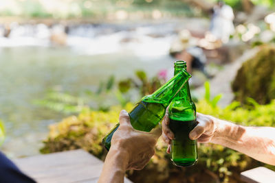 Senior man toasting with bottle beer together with his son on vacation.