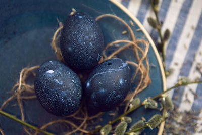 Decoration design blue easter eggs lie on a plate with a willow on a striped fabric background