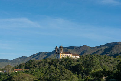 Scenic view of building and mountains against blue sky