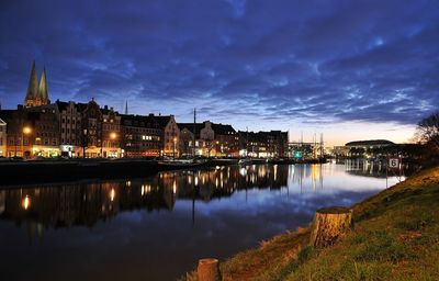 River by illuminated city against sky at night