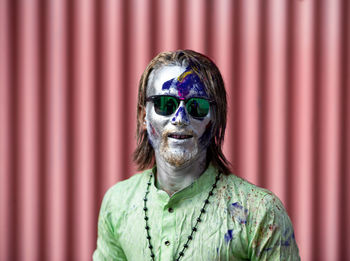 Portrait of young man wearing sunglasses against pattern wall.