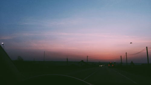 Cars on street against sky at sunset