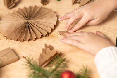 Girl makes christmas tree decorations out of paper with her own hands. step 3