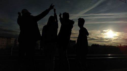 Silhouette friends standing against sky during sunset