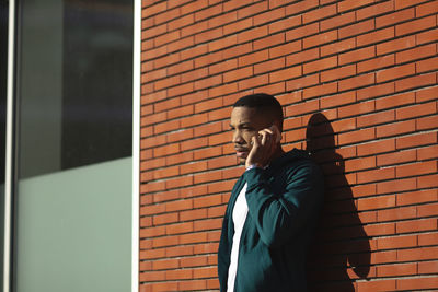 Man standing against brick wall