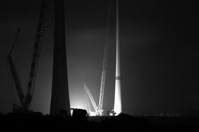 Low angle view of silhouette cranes against sky at night