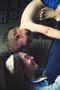 Woman playing with son on sofa in living room at home