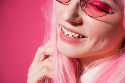 Close-up of woman wearing braces against colored background