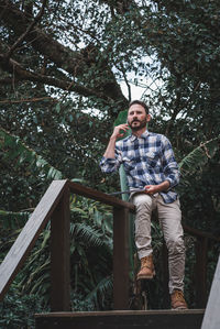 Portrait of young man standing on footbridge