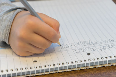 Cropped hand of child writing in book