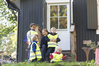 Happy teacher with children outside preschool building