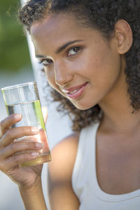 Portrait of smiling young woman holding drinking glass