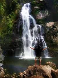 Full length of woman standing on rock in forest