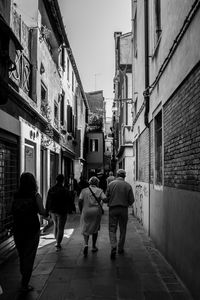 Rear view of people walking on street in city