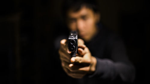 Close-up of man holding gun in darkroom