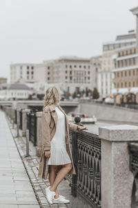 Portrait of young woman standing against buildings in city