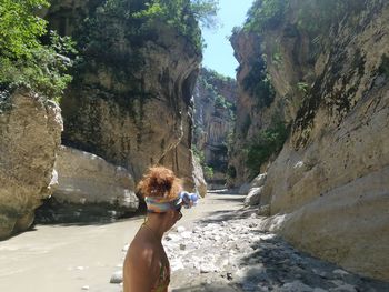 Rear view of woman wearing sunglasses on rock