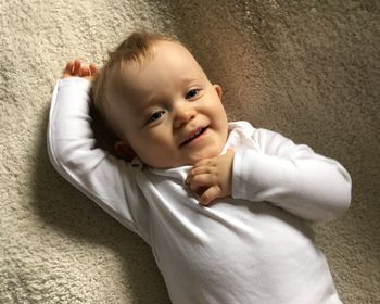 Portrait of smiling baby boy relaxing on rug at home