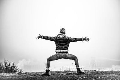 Man with arms outstretched on field against sky