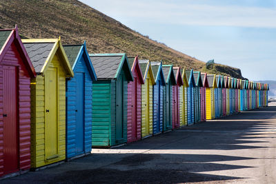Multi colored huts on beach by building against sky